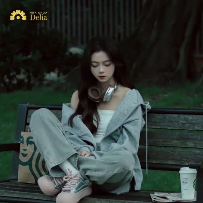 Ngồi trên ghế dài, tay vòng qua gối