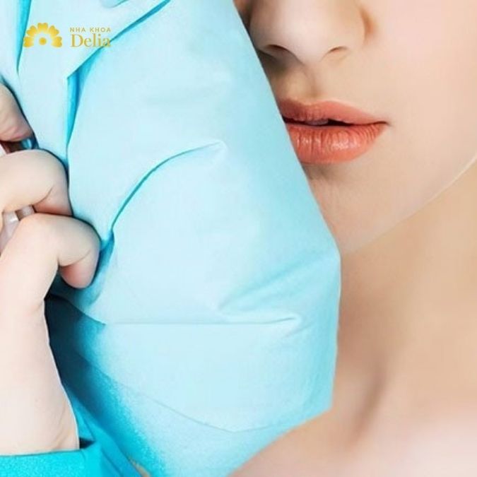 Áp dụng chườm lạnh ngoài má trong 24 giờ đầu tiên sau khi nhổ răng để giảm sưng và giảm đau